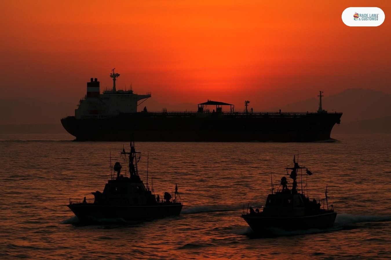 Buque tanquero de ADNOC transitando el Estrecho de Ormuz con patrulla naval en primer plano al atardecer.